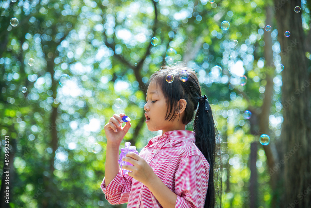 Adorable happy cute girl playful foam bubbles in green playground in summer outdoors. Funny Cheerful girl in the park with happy times. Adorable happy cute girl playful foam bubbles in green playground in summer outdoors. Funny Cheerful girl in the park with happy times.