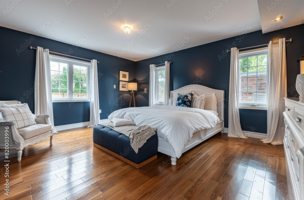 Master bedroom with dark blue walls, white furniture and wood floors in home for sale