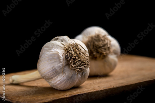garlic on wooden board on black background
