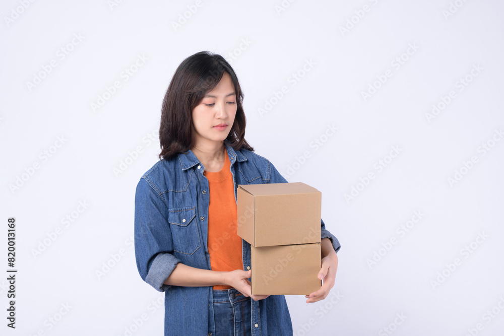 young asian woman wearing orange t-shirt and denim shirt holding parcel box isolated on white studio background, Delivery courier and shipping service concept. young asian woman wearing orange t-shirt and denim shirt holding parcel box isolated on white studio background, Delivery courier and shipping service concept.