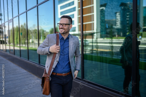 Wallpaper Mural Confident young businessman with shoulder bag standing on sidewalk by modern glass building in city Torontodigital.ca