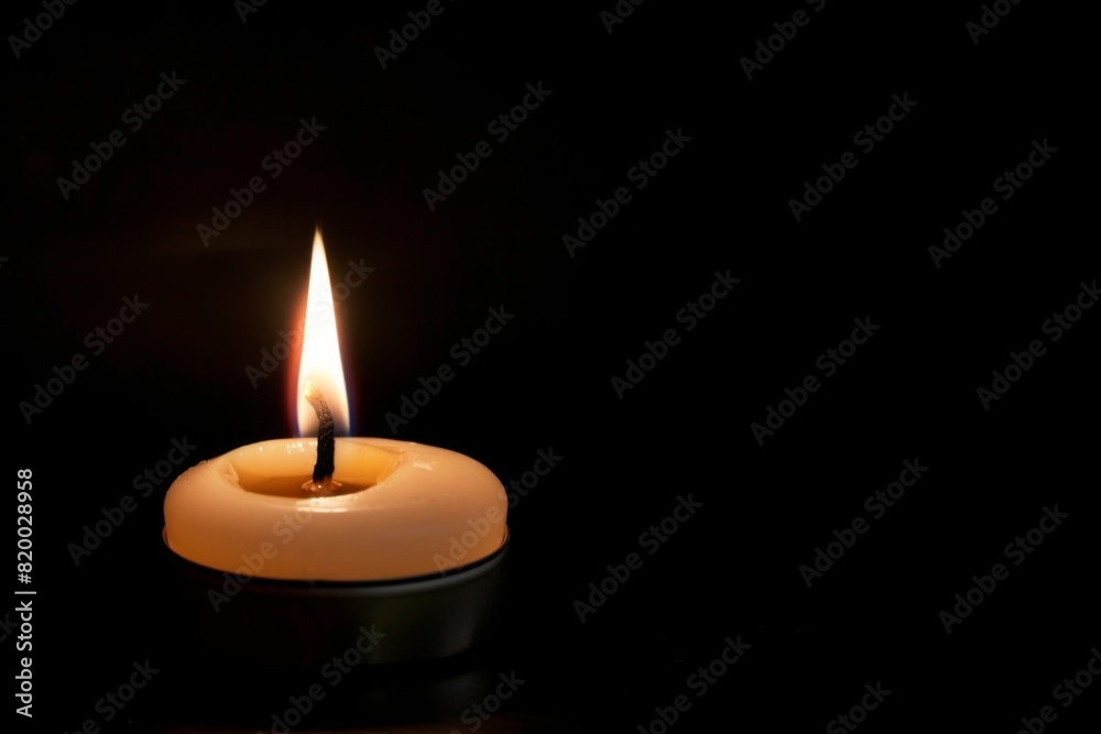 White Candle Burning in the Dark, Isolated on Black Background, Symbolizing Memorial Day Remembrance.