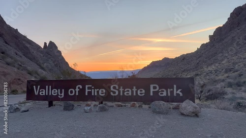 The entrance sign for Valley of Fire State Park with a Beautiful Sunrise resembling fire in the Background - Nevada, USA photo