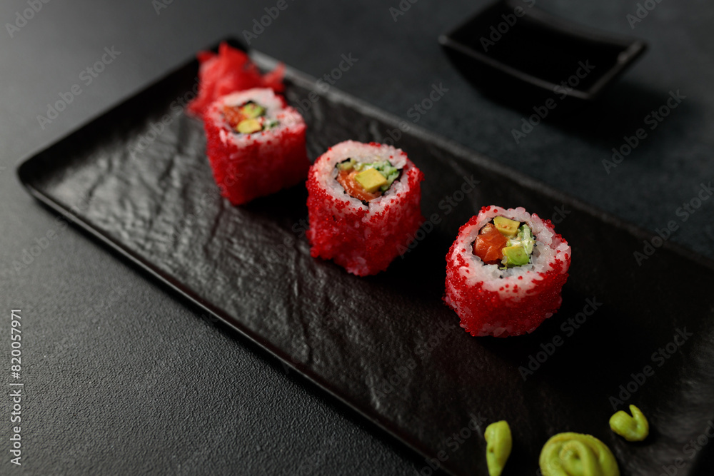 Japanese food: sushi, California roll with salmon, avocado, tobiko caviar, cucumber. Black background Japanese food: sushi, California roll with salmon, avocado, tobiko caviar, cucumber. Black background