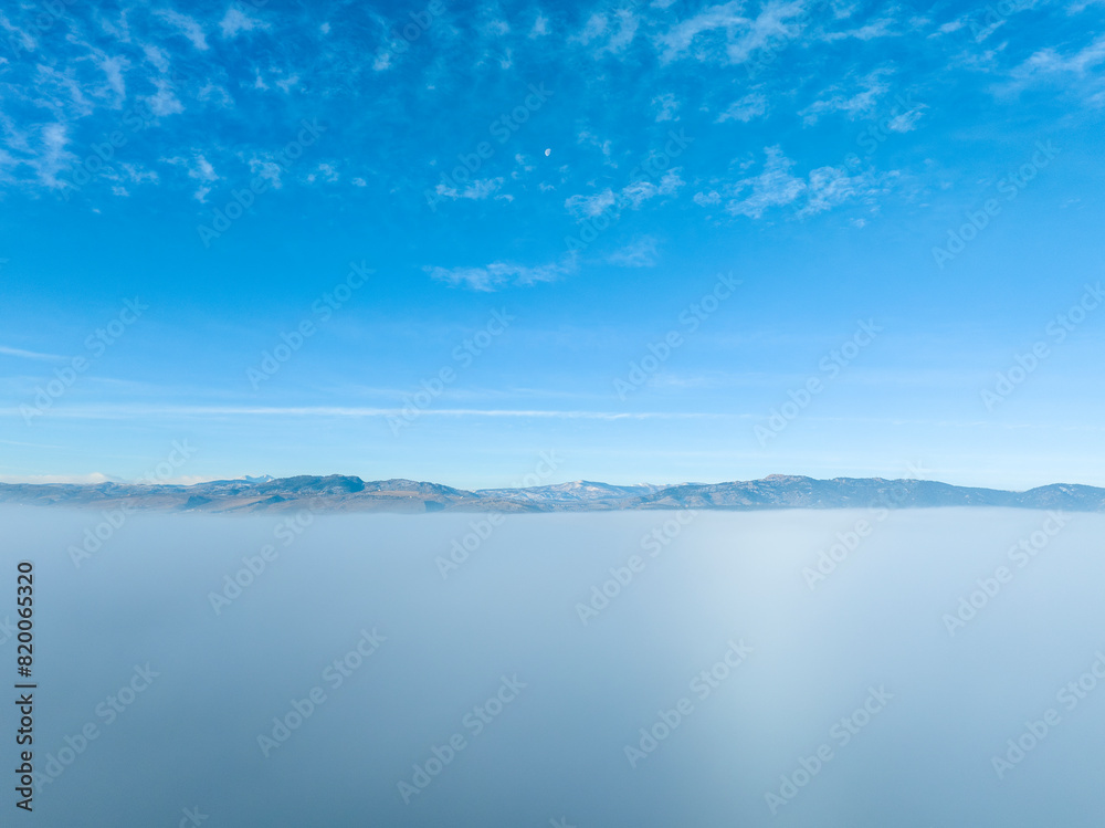Front Range of Rocky Mountains in in Colorado with a fog blanket covering city of Fort Collins, winter morning aerial view