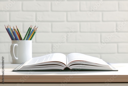 pile of books and pencils on the desk on white brick wall background