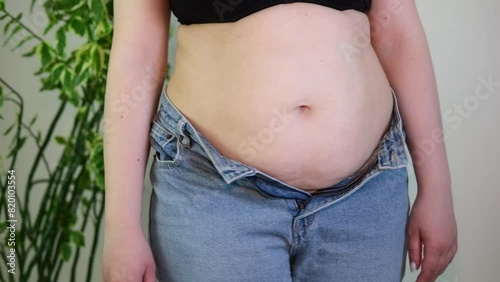Cropped midsection of obese woman with fat upset about belly. Fat woman in tight clothes is worried about dieting lifestyle concept.