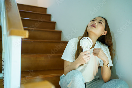 Asian woman using portable mini electric fan in the hotter day.