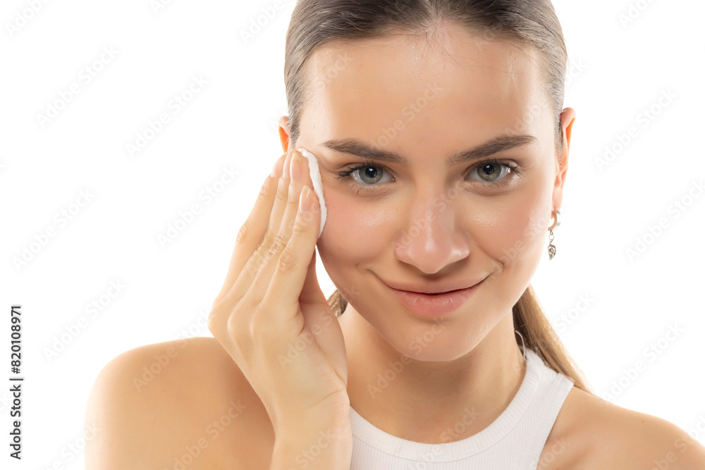 Portrait of a young smiling woman removing her make-up on a white background Portrait of a young smiling woman removing her make-up on a white background