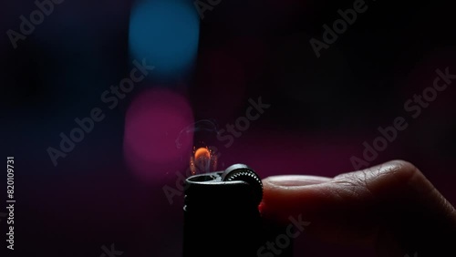 Flicking a Lighter with a Thumb in Macro and Slow Motion, Sparks Ignite the Gas Generating Flame Dancing on a Purple Background photo