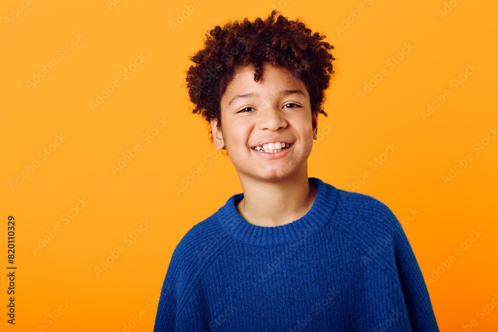 Bright and cheerful a joyful young african american boy in a blue sweater against a vibrant orange backdrop Bright and cheerful a joyful young african american boy in a blue sweater against a vibrant orange backdrop