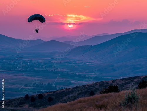 A man is flying a parachute over a beautiful mountain landscape. The sky is filled with a warm  orange glow as the sun sets behind the mountains. The scene is serene and peaceful  with the man