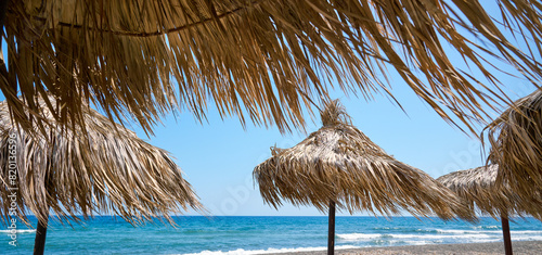 Fototapeta Naklejka Na Ścianę i Meble -  Paralia Karterados, wild volcanic sand beach with thatched umbrellas. Greek islands, Santorini, European vacations.