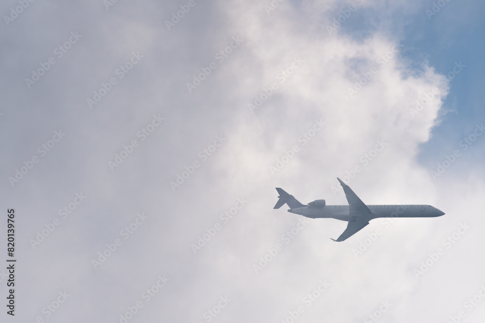 Low angle view of the airplane flying out of the white clouds Low angle view of the airplane flying out of the white clouds