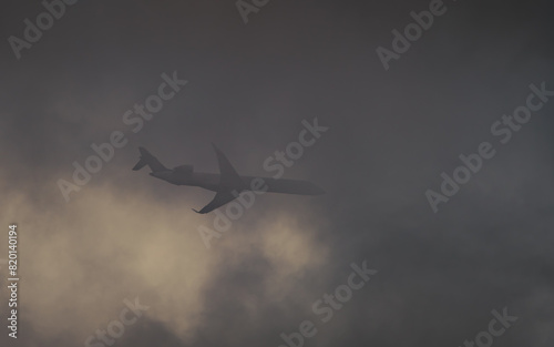 Airplane in the sky flying trough the dark cloud