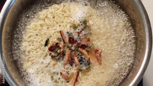 Boiling instant noodles with spices in a pot on the stove in the kitchen photo