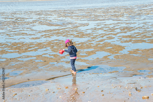 Canvas Print One little girl (back view) in a atlantic ocean during low tide