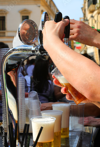 Bartender pouring a glass of ice-cold lager during an outdoor party photo