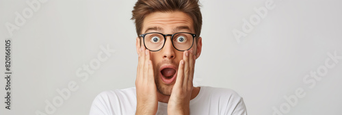 Surprised man with glasses, holding his face with both hands, expressing shock or astonishment