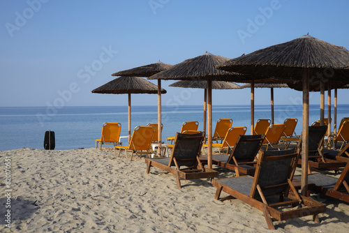 Sandy beach with sunbeds and straw umbrellas on the Olympic Riviera, Nei Pori, Pieria - Greece photo