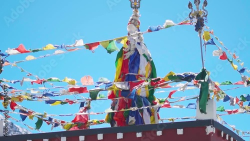 Slow motion shot of colorful Buddhist Tibetan prayer flags waving against clear blue sky as seen from Kunzum Pass on the way towards Spiti Valley in Himachal Pradesh, India. Prayer flags in Himalayas.