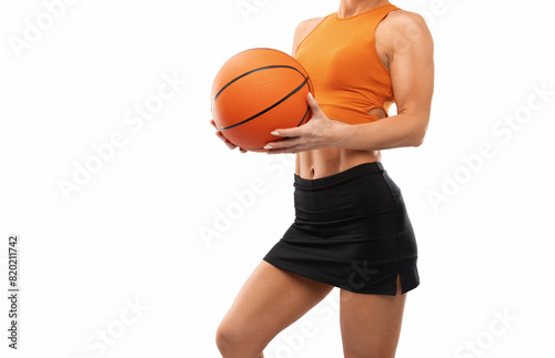 A beautiful slender girl athlete in shorts and in orange yop plays basketball. photo