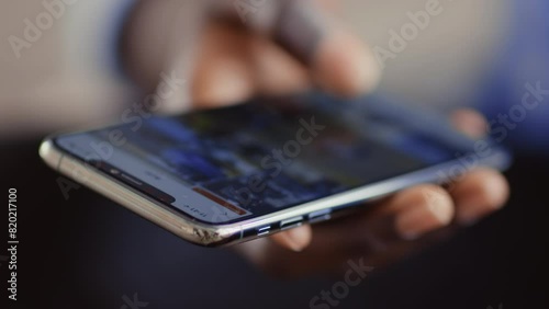 Online life. African guy scrolling social media app on cellphone, close up