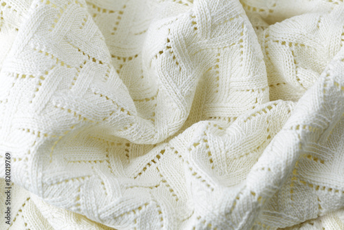 A white knit blanket with a pattern of zigzags. The blanket is soft and cozy, perfect for snuggling up on a cold day