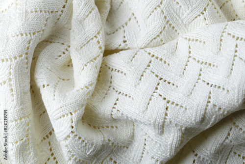 A white knit blanket with a pattern of zigzags. The blanket is soft and cozy, perfect for snuggling up on a cold day