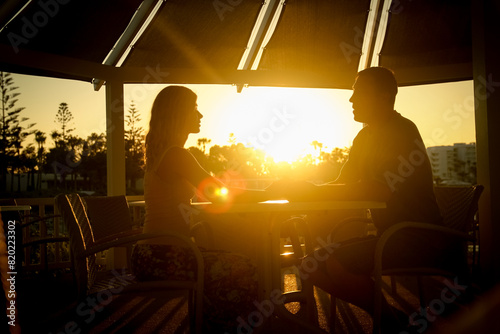 happy couple at a table by the sea at sunset nature