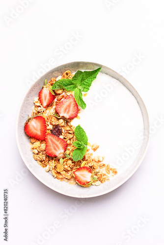 Greek yogurt with granola and fresh fruit on white marble background top view, vertical image. Healthy tasty homemade breakfast concept.