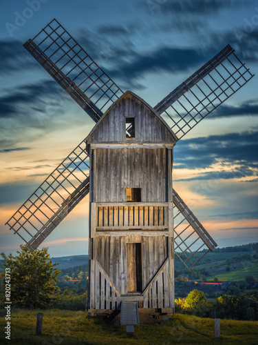 portrait view to back side of old wooden windmill in twilight lights under dark sky