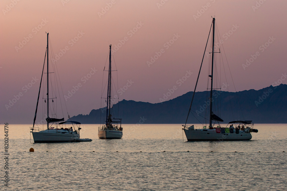 Sailing boat on bleu sunset background. Sailing boat on the sea. A sailboat at anchor in the Gulf of Porto in Corsica.