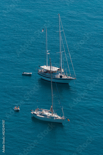 Sailboats at anchor in Corsica. Sailboats floating on the calm blue sea. Coastal summer landscape of Corsica