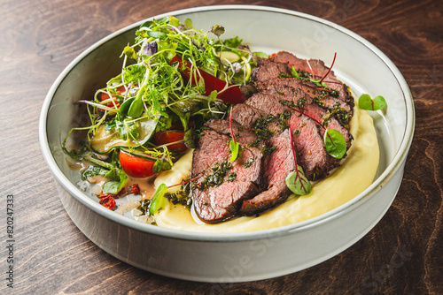 Sliced beef with herbs, served alongside puree and a side salad.