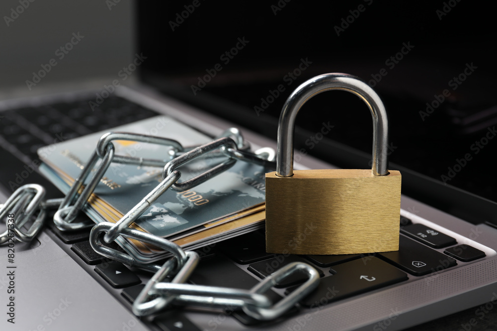 Cyber security. Metal padlock, chain and credit cards on laptop, closeup Cyber security. Metal padlock, chain and credit cards on laptop, closeup