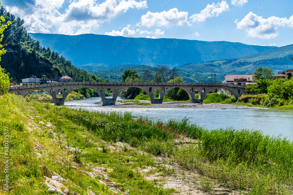 Fototapeta premium A view along the bank of the River Osum towards the Gorica bridge in Berat, Albania in summertime 