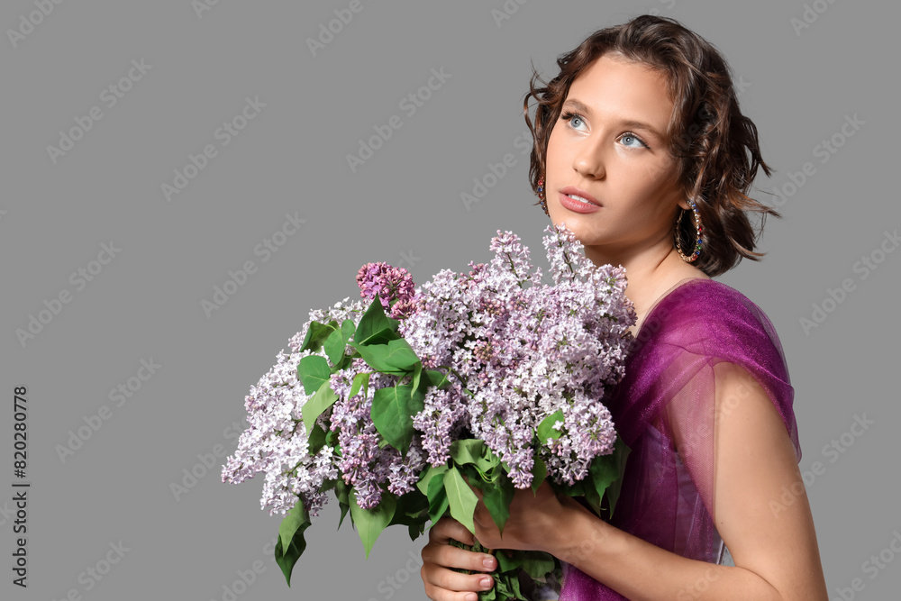 Beautiful young woman with bouquet of blooming lilac flowers on grey background