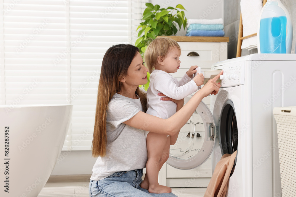Mother with her daughter washing baby clothes in bathroom Mother with her daughter washing baby clothes in bathroom