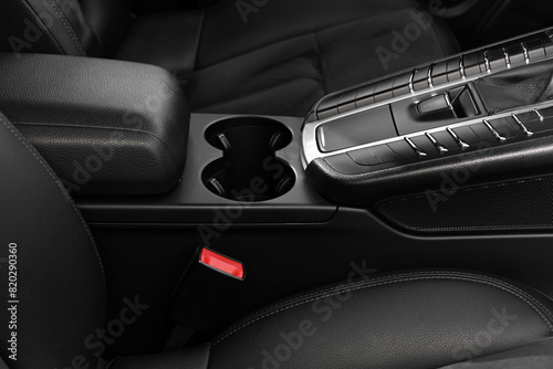 Cup holders and seat inside of modern black car, closeup photo