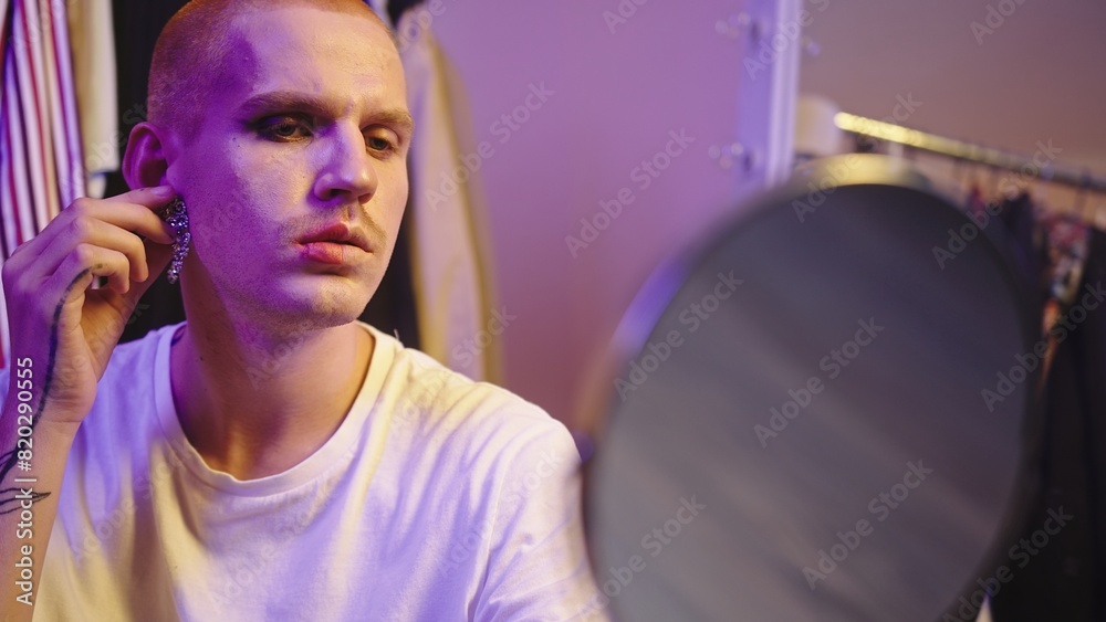 Fototapeta premium Close-Up: LGBT Individual Trying on Earrings by Large Mirror