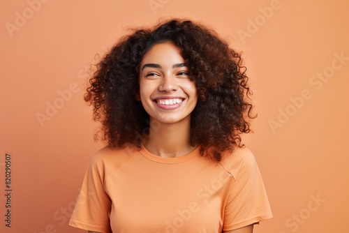 A woman with curly hair is smiling and wearing an orange shirt © MediaRaw