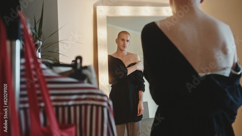 Foto Extravagant crossdresser adjusting dress in dressing room
