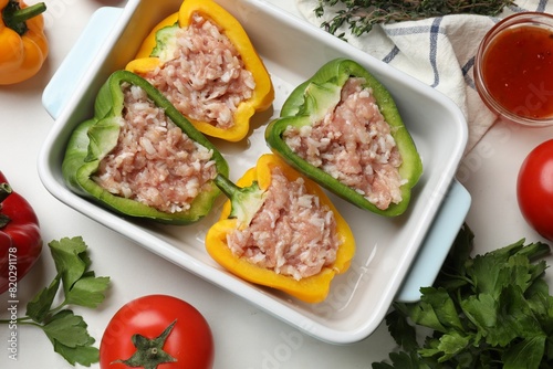 Raw stuffed peppers and ingredients on white table, flat lay