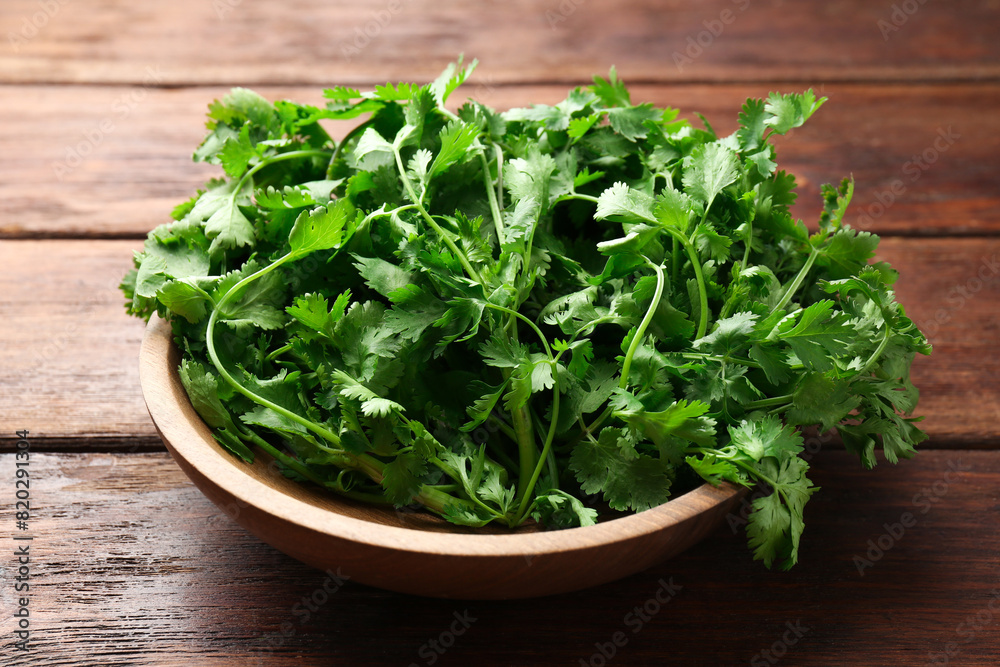 Fresh coriander in bowl on wooden table, closeup Fresh coriander in bowl on wooden table, closeup