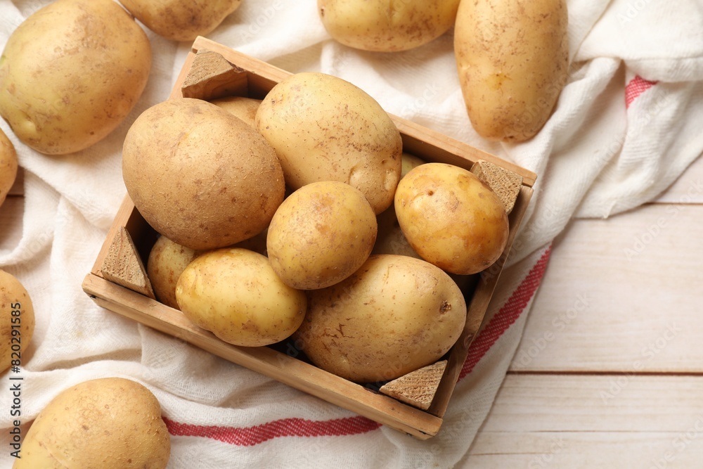 Raw fresh potatoes with crate on light wooden table, top view Raw fresh potatoes with crate on light wooden table, top view