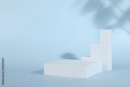 Presentation of product. Podiums and shadows on light blue background. Space for text