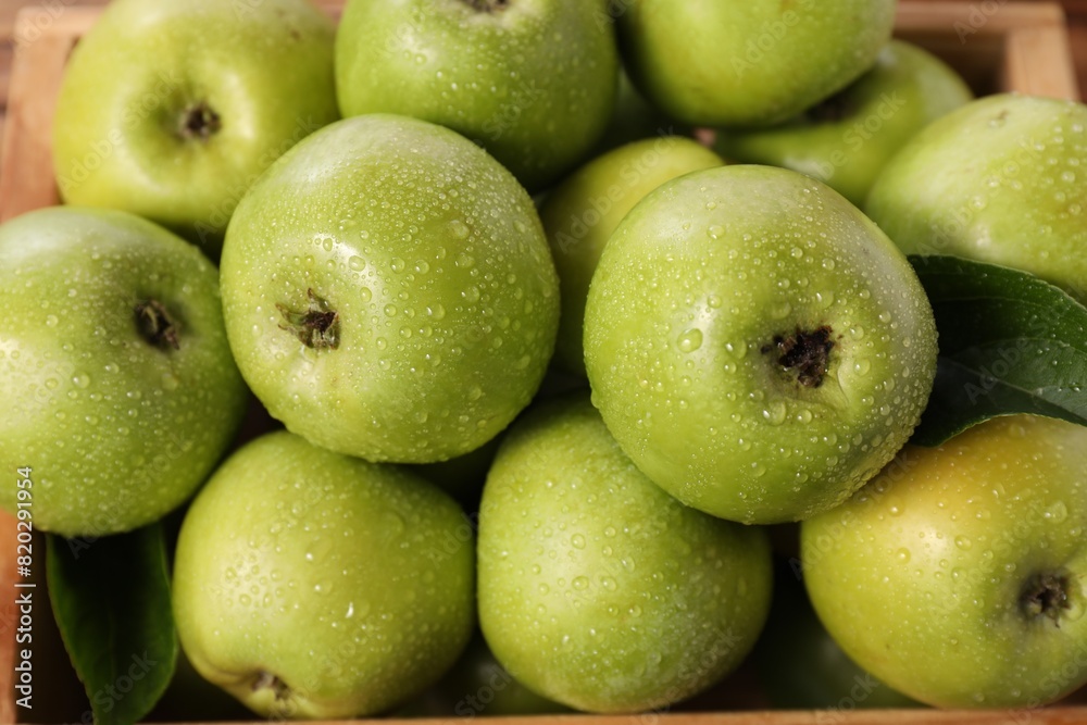 Obraz premium Fresh green apples with water drops in crate, closeup