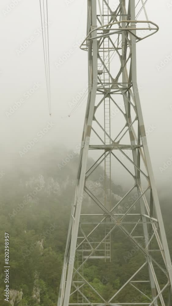 View from the cable car cabin high in the mountains amidst dense clouds. Forest below. View from the cable car cabin high in the mountains amidst dense clouds. Forest below.