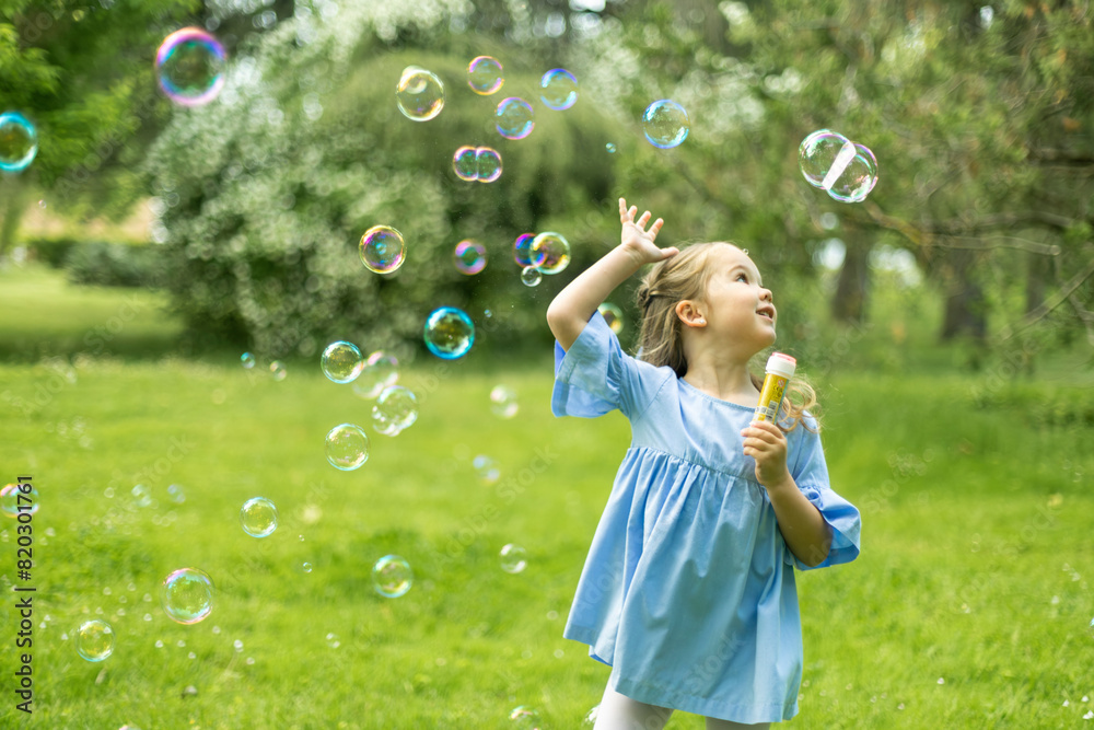Young girl playing with bubbles in vibrant park setting. Young girl playing with bubbles in vibrant park setting.